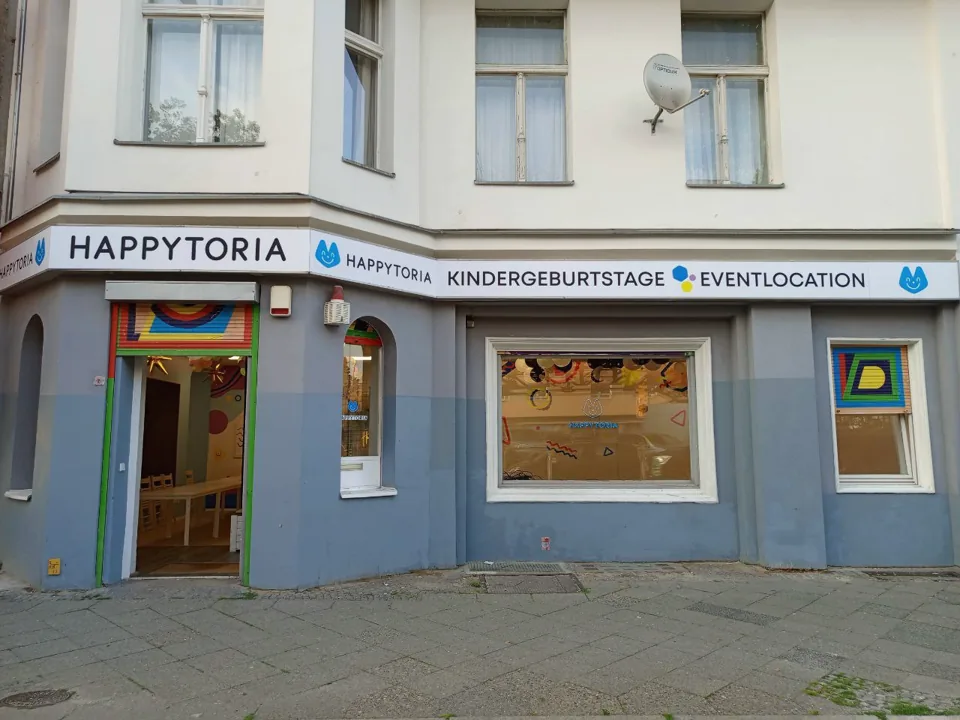 Durchgehendes Fassadenschild über Eingang und Fenster eines Eckladens