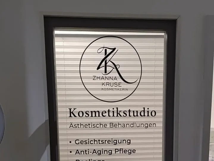 Aus Folie geschnittenes Logo und Leistungsliste auf einer Glastür