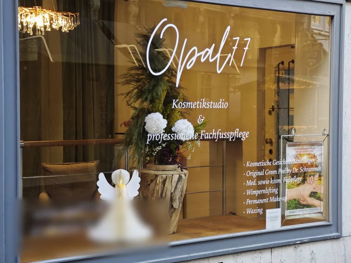 Schaufenster eines Kosmetikstudios mit weißer Folienschrift und Leistungsliste