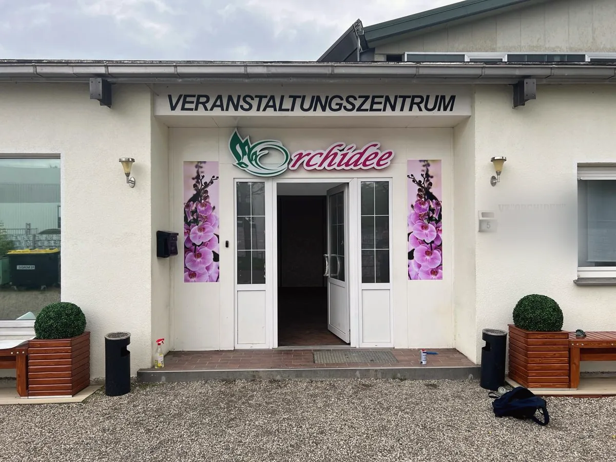 Eingang eines Veranstaltungszentrums mit bedruckten Orchideen-Paneelen neben der Tür